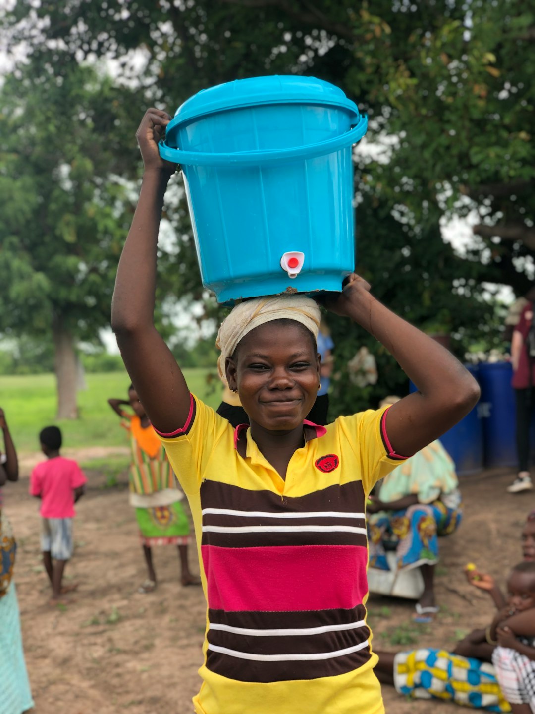 boy-in-yellow-and-black-stripe-polo-shirt-holding-blue-plastic-bucket-ugo71dhukug