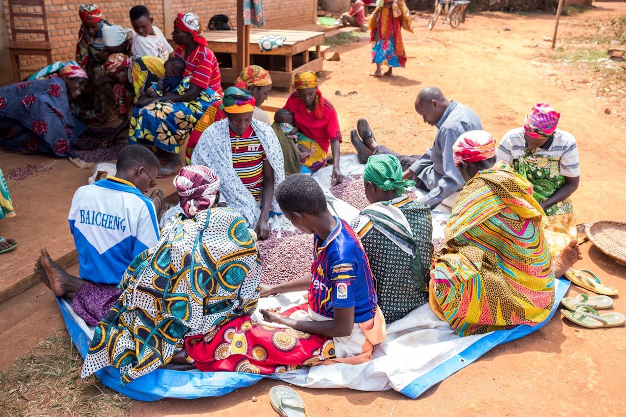 A group of African villagers engaging in sorting colorful fabrics outdoors.